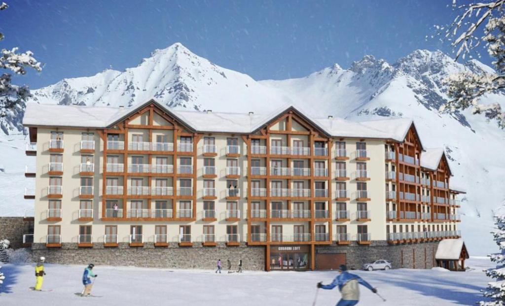 een groot gebouw met een met sneeuw bedekte berg op de achtergrond bij New Gudauri Loft 2 in Goedaoeri