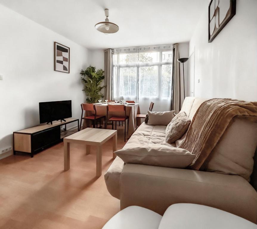 a living room with a couch and a table at Appartement proche Paris, parking, centre-ville in Châtillon