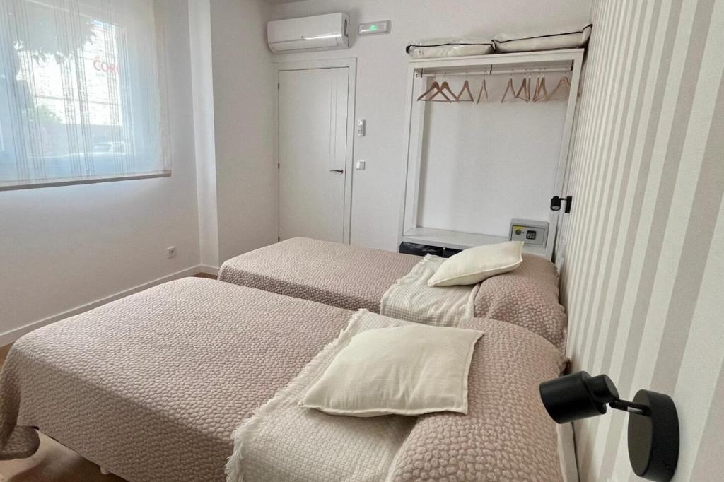 twee bedden in een kleine kamer met een raam bij Apartamento Xogo da Ola En el camino De Santiago in Porriño