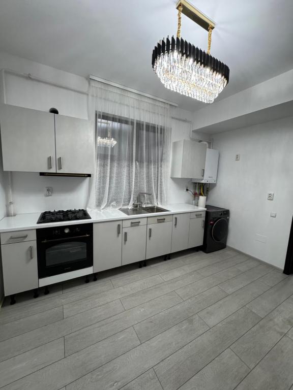 une cuisine avec des armoires blanches et un lustre dans l'établissement Apartament Modern Penthouse Rm Valcea, à Valcea