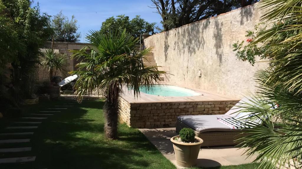 una piscina in un cortile con una panchina e una palma di La Bastide de Saint Martin a Saint-Martin-de-Ré