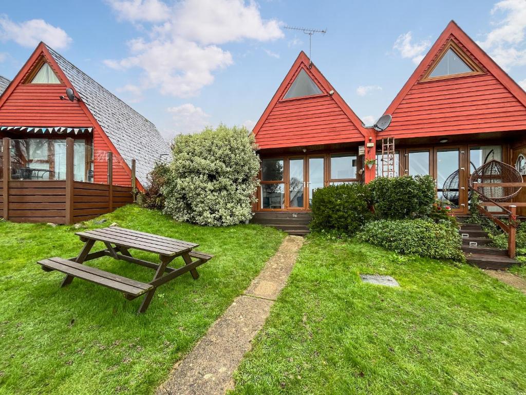 een rood huis met een picknicktafel ervoor bij Chalet Lodge - Uk51029 in Kingsdown