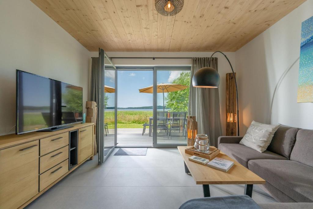 ein Wohnzimmer mit einer Couch, einem Fernseher und einem Tisch in der Unterkunft Ferienhaus am See LEE - Vogteihof am Bodden in Streu
