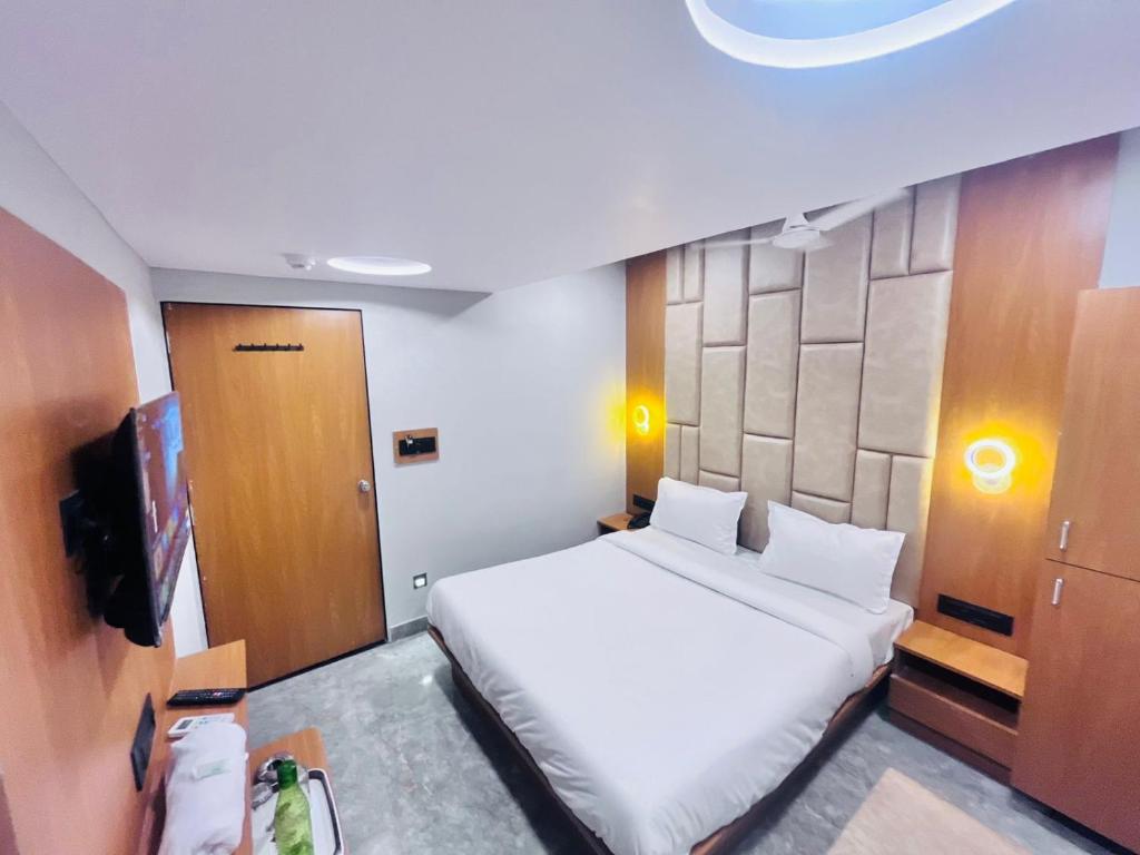 a bedroom with a white bed and a television at Hotel Sun Lake in Ahmedabad