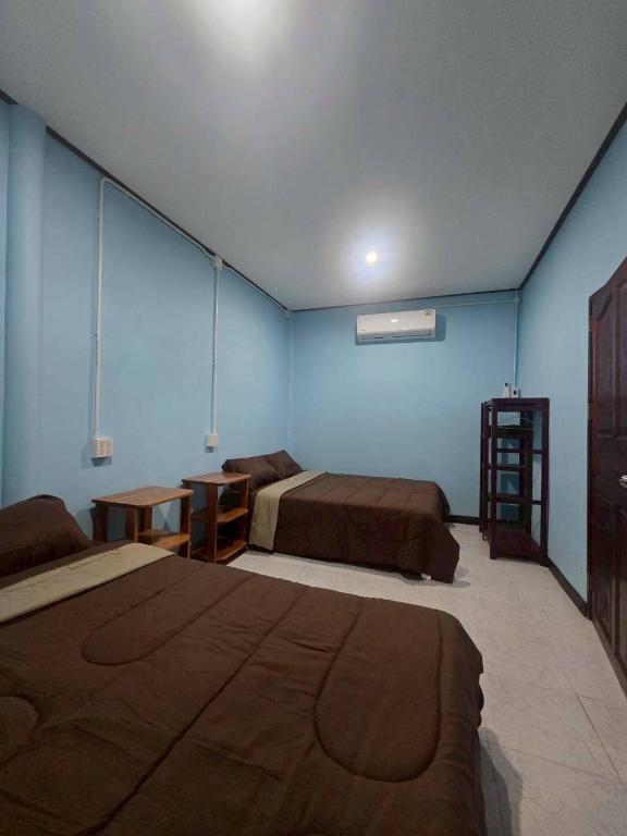 a bedroom with two beds and a blue wall at Mook Lucky family in Ban Chao Mai