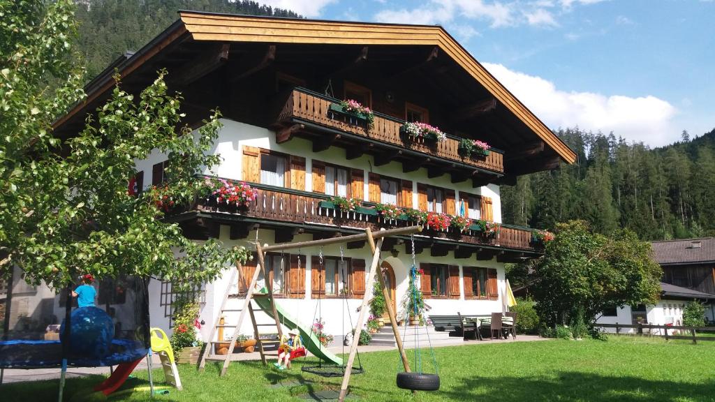ein großes Gebäude mit einem Balkon und einem Spielplatz in der Unterkunft Ferienwohnungen Weberbauer in Sankt Martin bei Lofer