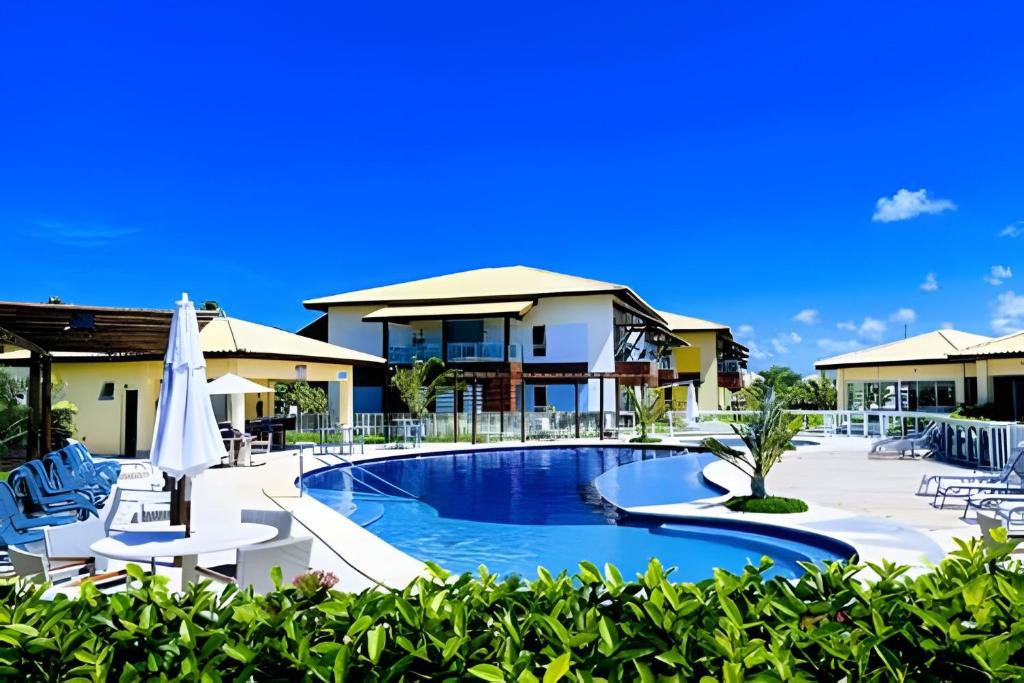 una piscina in un resort con sedie e ombrellone di Village Baixio Frente ao mar a Baixio