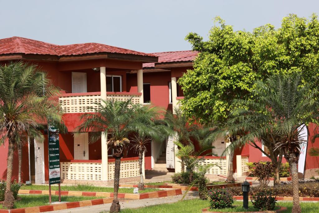 a red house with palm trees in front of it at Complejo Caribe in Monte Alen