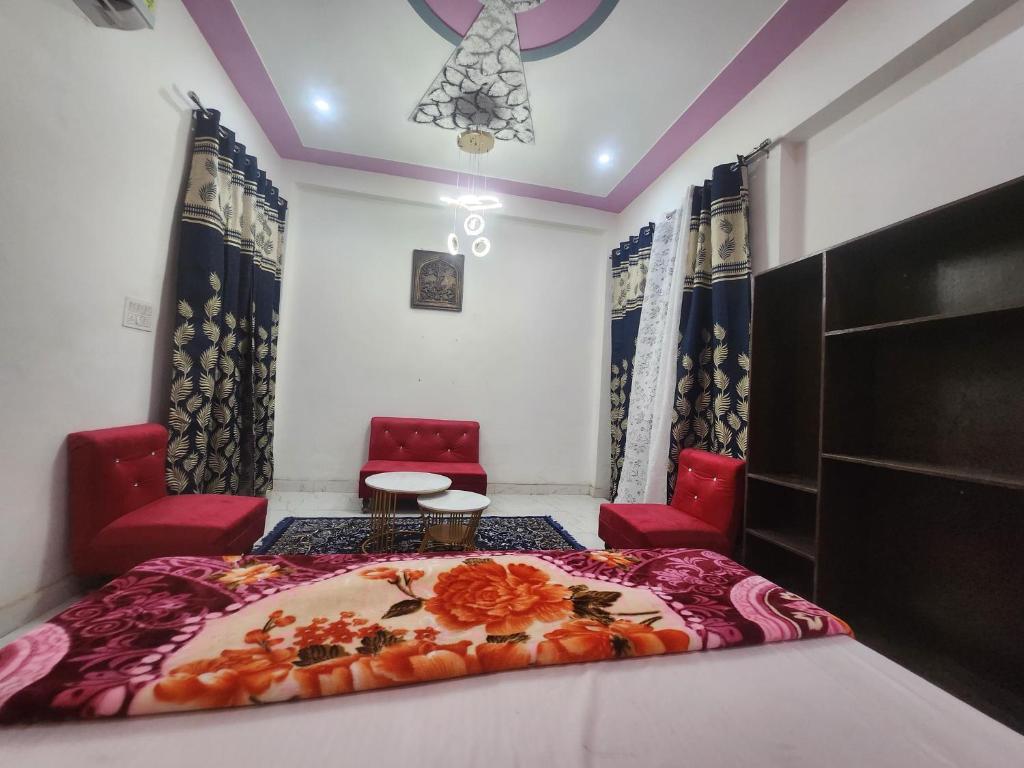 a room with a bed and two red chairs at Dks villa Homestay in Agra