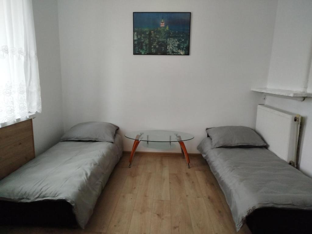 een kamer met 2 bedden en een glazen tafel bij Iriska Home in Warschau