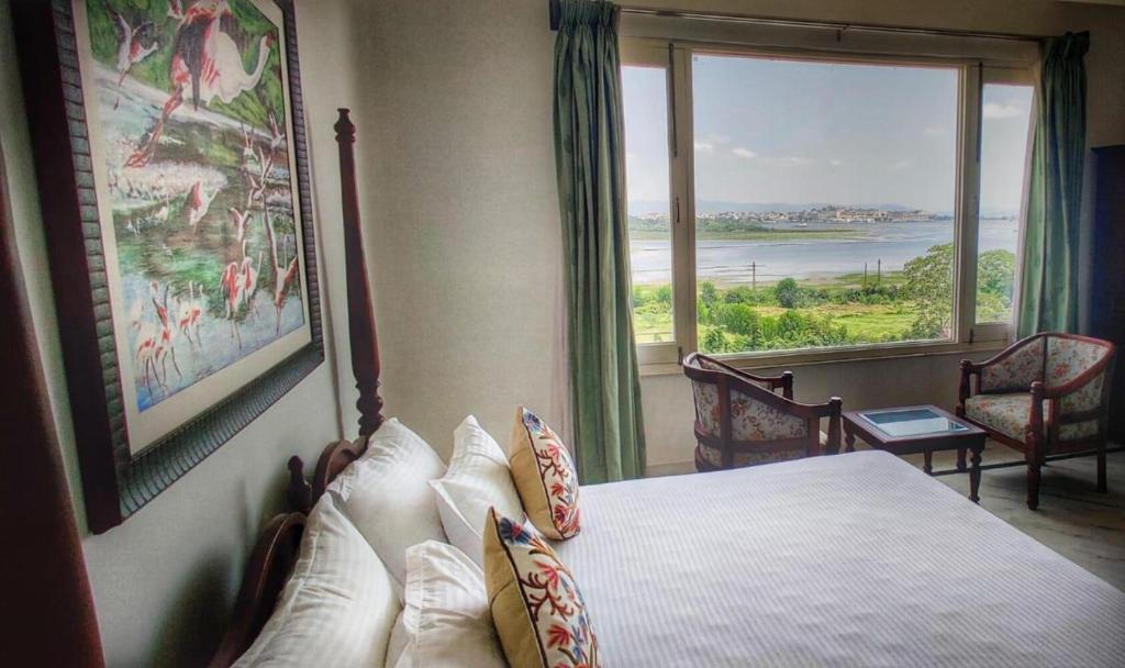 una camera da letto con un letto e una grande finestra di The Devi Lake Stay Udaipur a Udaipur