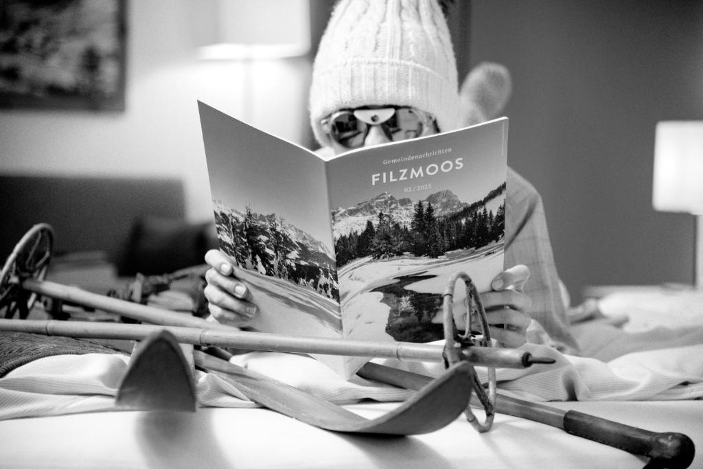 Een man leest een boek in bed. bij Hotel Unterhof in Filzmoos