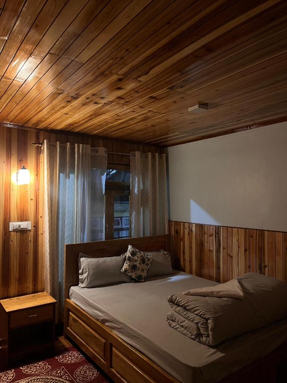 a bed with a wooden headboard in a bedroom at Chyajalo homestay in Darjeeling