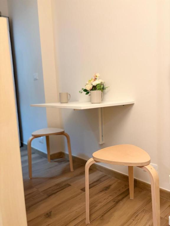 ein Tisch und zwei Hocker und ein Tisch mit Blumen darauf in der Unterkunft Gianduia in Turin