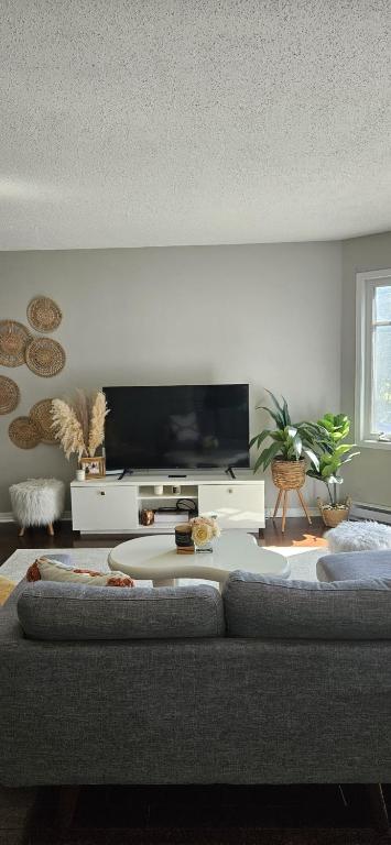 a living room with a couch and a flat screen tv at Boho Retreat 3BD Condo Close to Ottawa in Gatineau