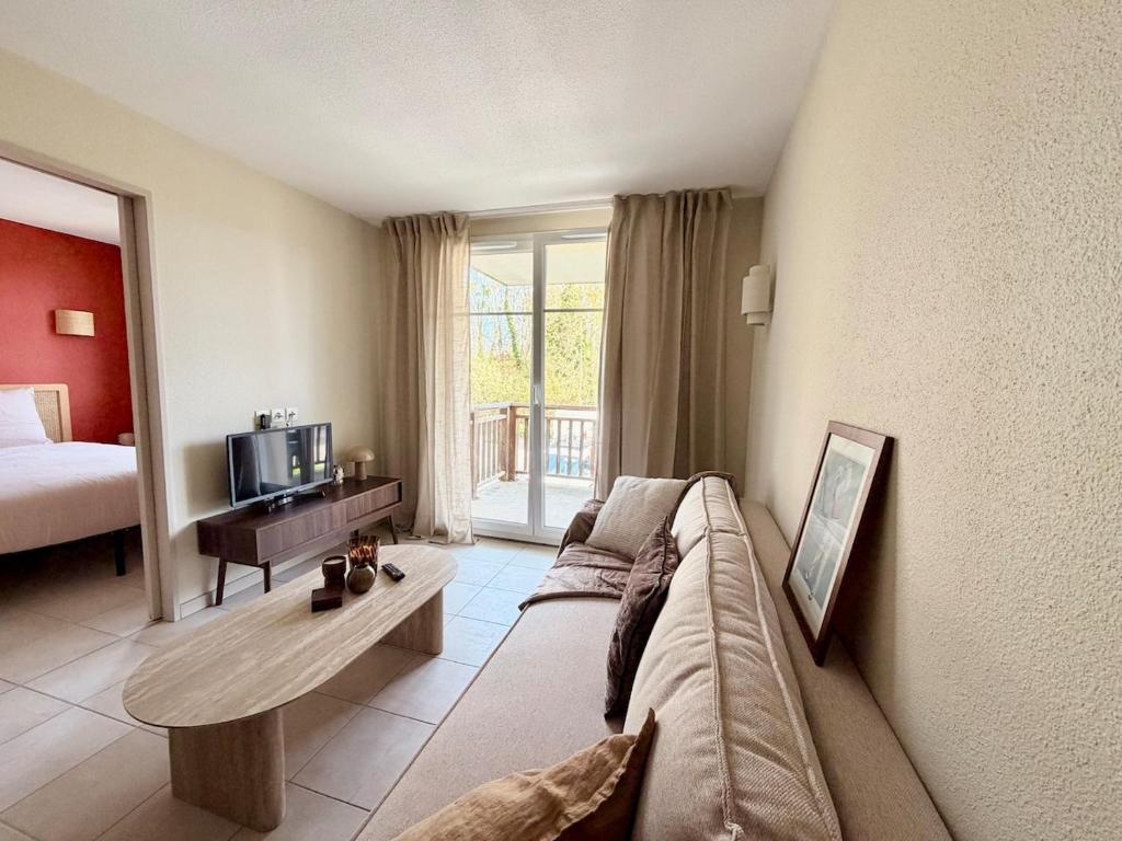 een woonkamer met een bank en een televisie bij Le Clos de Beaune in Levernois