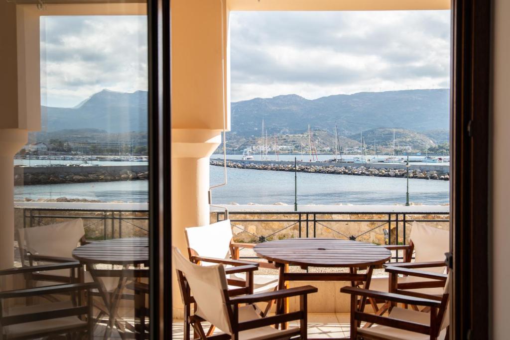 a balcony with tables and chairs and a view of the water at Renas Guesthouse in Sitia