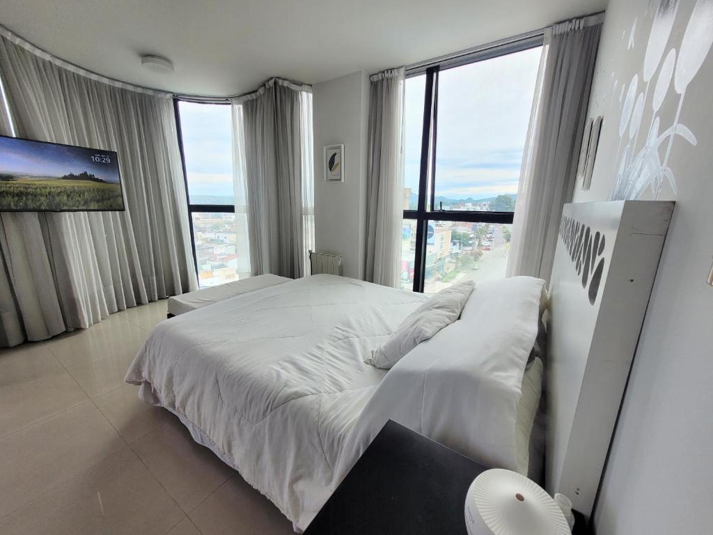a bedroom with a white bed and a large window at Apartamento Ejecutivo Premium Riviera Tower in Villa Carlos Paz