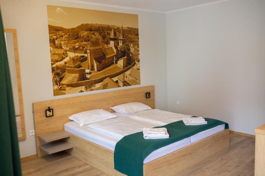 a bedroom with a bed with a painting on the wall at Pensiunea Draser in Şeica Mică
