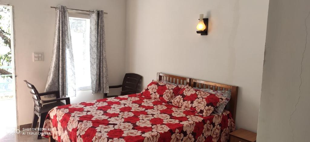 a bedroom with a bed with a red and white quilt at Oak Hill Cottage in Mussoorie
