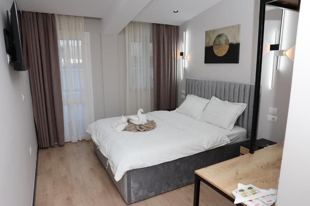 een slaapkamer met een groot bed met witte lakens bij Kremelo Hotel in Berat