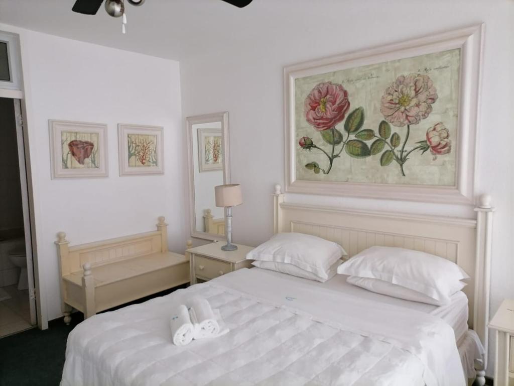 une chambre avec un lit blanc et un tableau au mur dans l'établissement Inyoni Rocks Cabanas 15, à Amanzimtoti