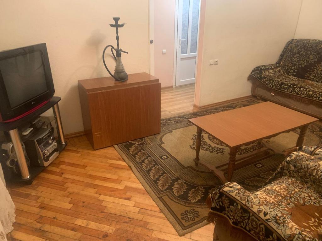 een woonkamer met een tv, een bank en een tafel bij Джермук 3-комнатная квартира in Dzjermoek