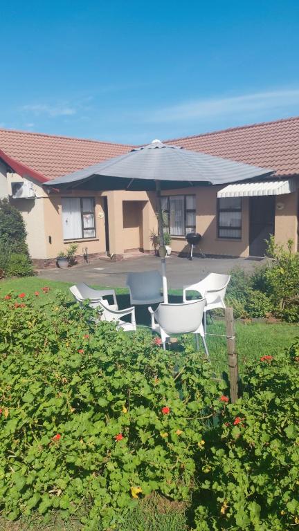 a group of chairs and an umbrella in a yard at Garden Cluster Home in Edenvale in Edenvale