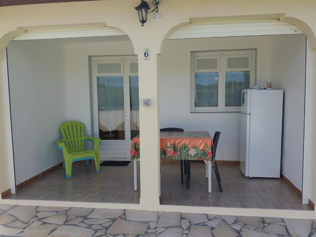 a dining room with a table and a green chair at Le Paradis bleu in Sainte-Anne