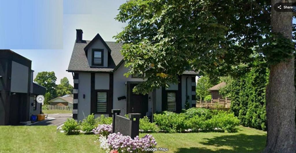a black house with a tree in the yard at Modern 7 Bedroom Masterpiece on Portage Sleeps 16 in Niagara Falls