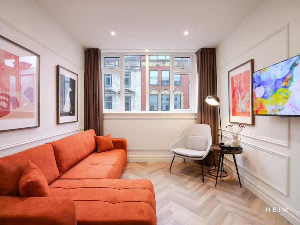 a living room with an orange couch and a window at Calico at The Heim Residences in Manchester