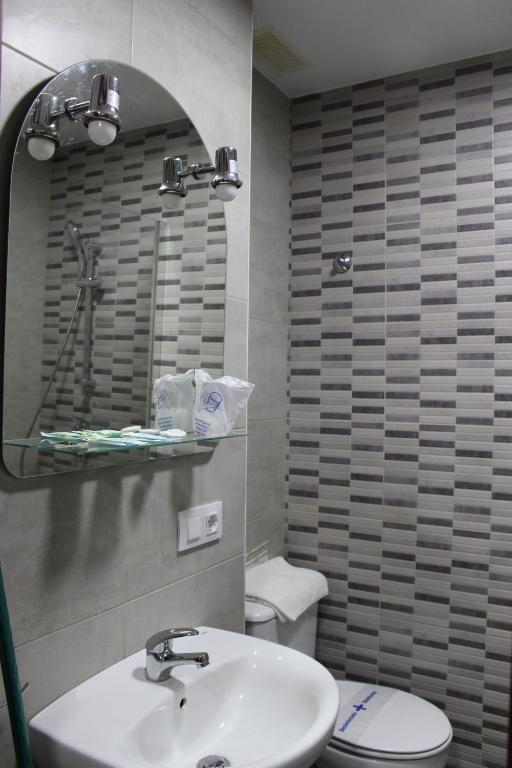 a bathroom with a sink and a toilet and a mirror at Apartamentos Bolonia Paraiso in Bolonia