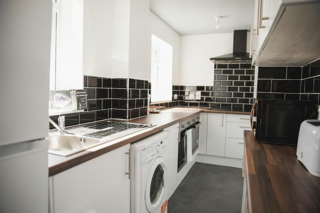 una cucina bianca con lavandino e lavastoviglie di Spaces Central House a Aylestone