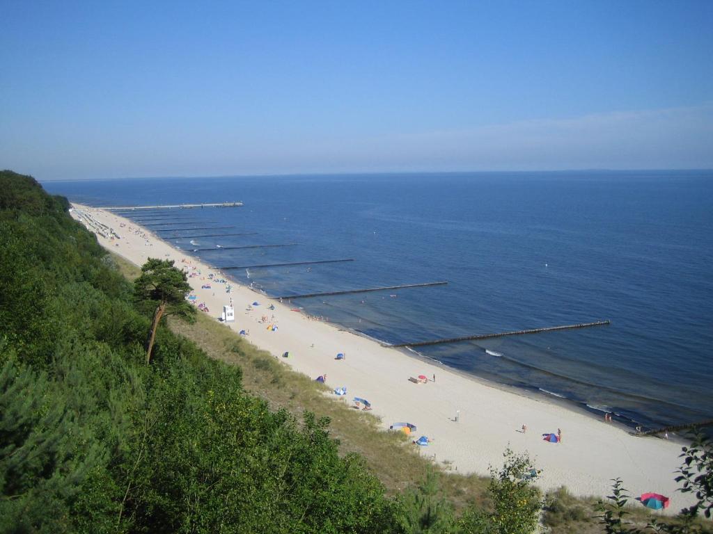 una playa con gente y sombrillas y el océano en Am Küstenwald en Ostseebad Koserow