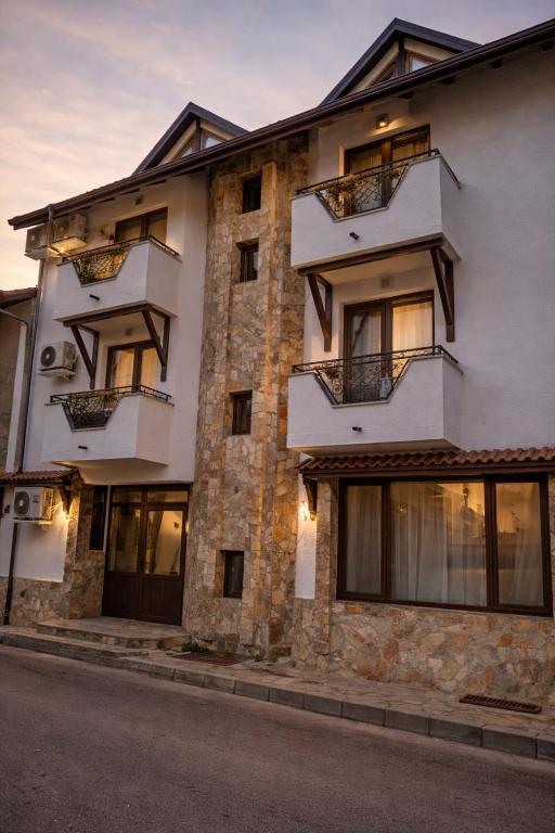 een groot wit gebouw met ramen aan een straat bij Хотел Ривърсайд Анекс in Bansko