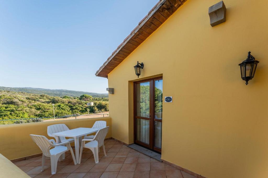 een terras met een tafel en stoelen op een balkon bij Cozy studio with shared pool in Vignola Mare