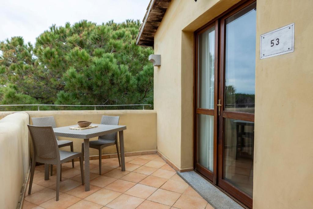 een terras met een tafel en stoelen op een balkon bij Functional studio with shared pool in Vignola Mare