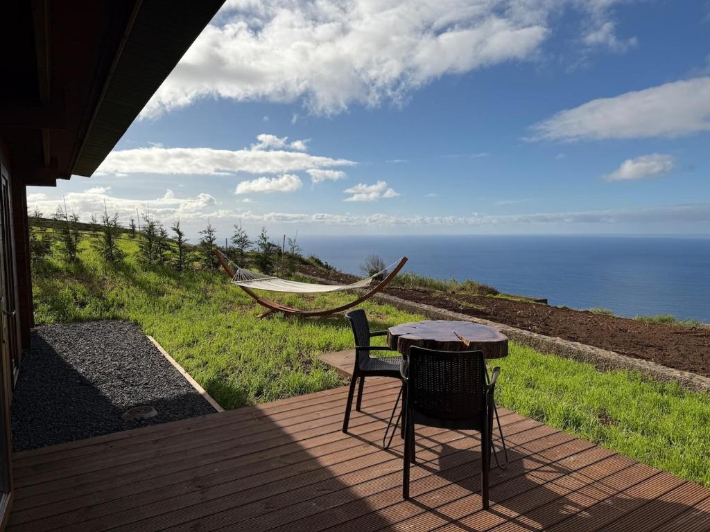 einen Tisch und Stühle auf einer Terrasse mit Meerblick in der Unterkunft Sunset Eco Shelter 1 in Ponta do Pargo