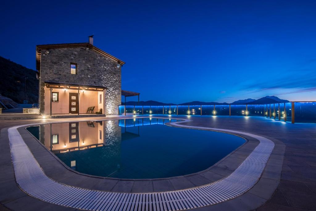 una piscina frente a un edificio por la noche en The View Village - Villas Suites & Spa, en Karpenisi