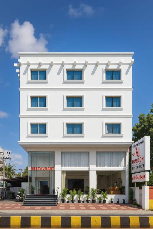 a white building with a sign in front of it at Hotel n pavilion in Mysore