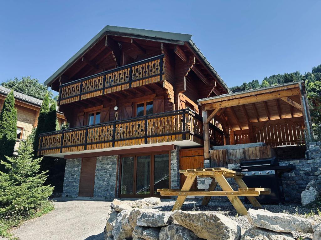 ein großes Holzhaus mit einem Picknicktisch davor in der Unterkunft Chalet individuel 8 pers à Chatel Porte du soleil avec Jacuzzi exterieur in Châtel