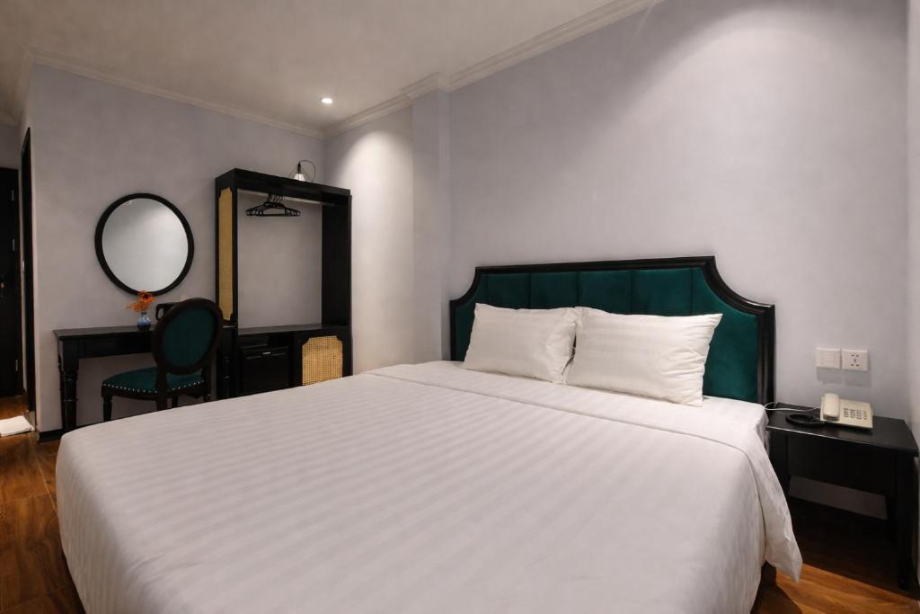 a bedroom with a large white bed and a mirror at Maya Central Hotel & Spa in Hanoi
