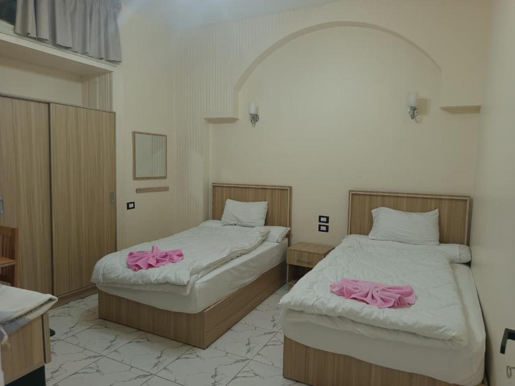 twee bedden in een kamer met roze handdoeken erop bij Calista Hotel in Caïro
