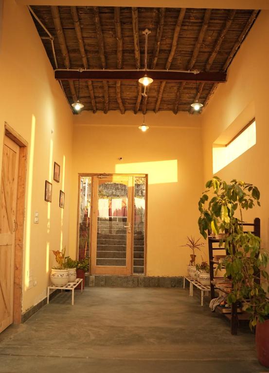 a hallway with a door and plants in a building at Hobo Hostel in Dharamshala
