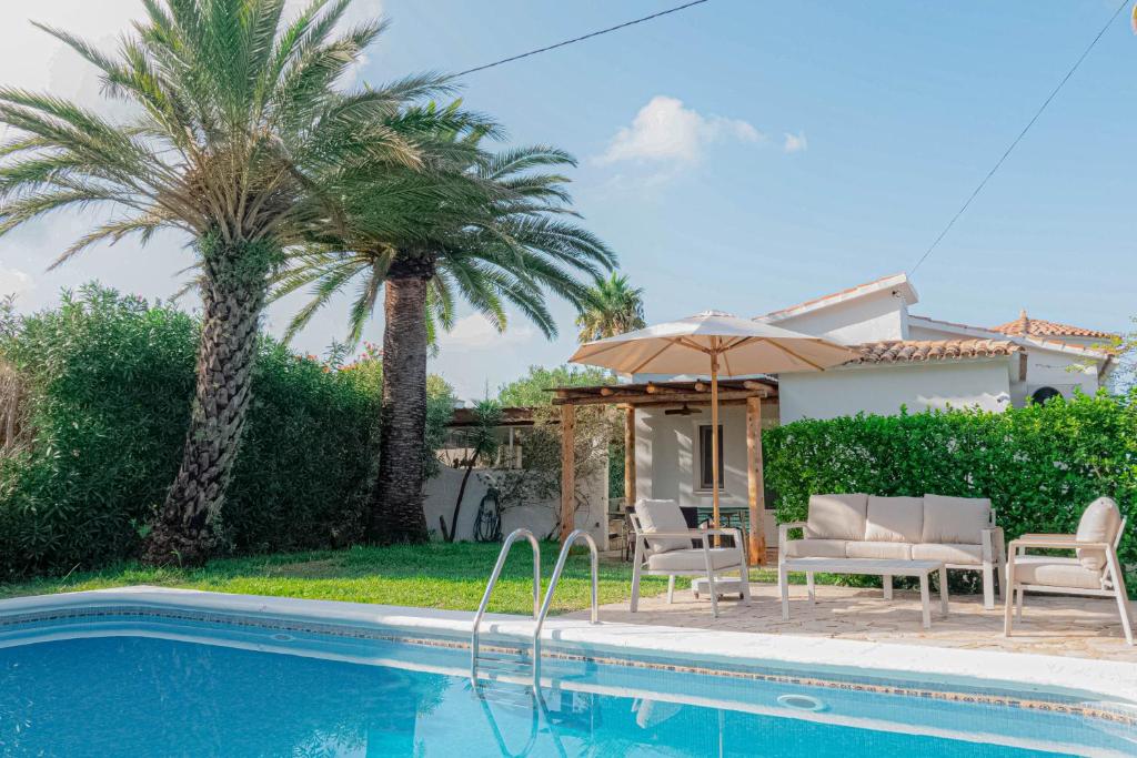 a villa with a swimming pool and palm trees at Casa MaJa in Denia