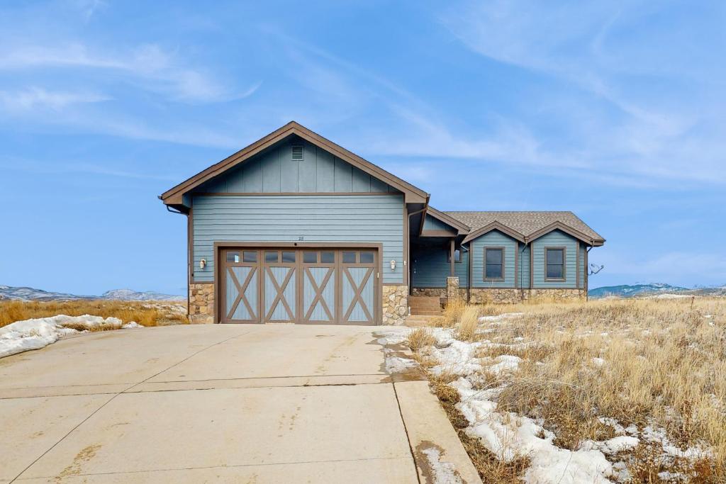 una casa blu con un garage in un campo di Silver Sage Sanctuary a Granby