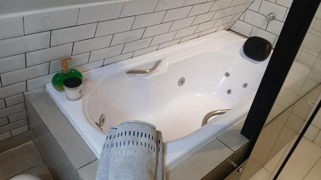 a white bath tub with a green bottle in it at Chalé romântico com hidro, lareira e churrasqueira na Serra in Serra Negra