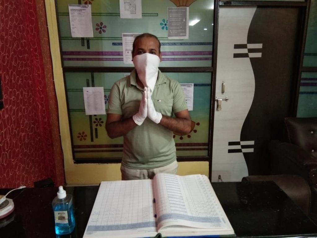 een man die voor een tafel staat met een masker op zijn gezicht bij SPOT ON Hotel Harry's 1 Near Select Citywalk Mall in New Delhi