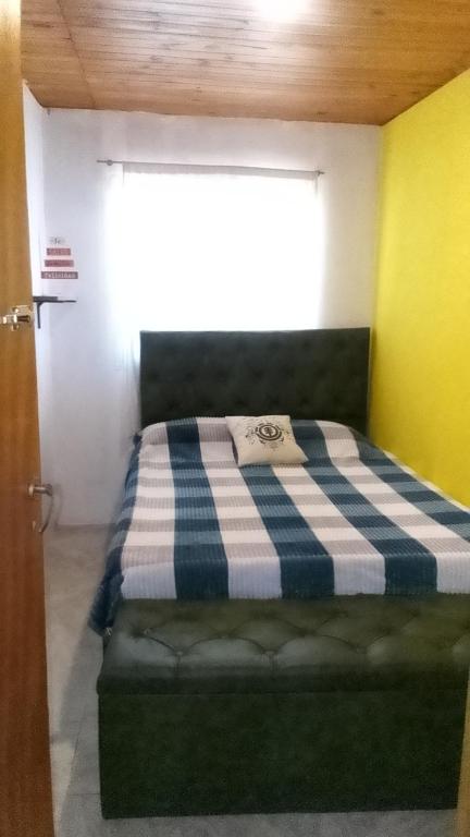 a bedroom with a bed with a checkered blanket on it at Los patos in Capilla del Monte