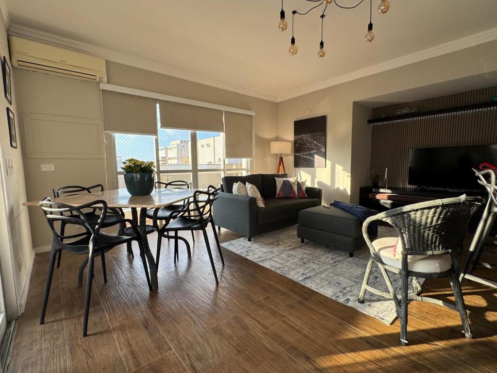 un salon avec une table, des chaises et un canapé dans l'établissement Linda Cobertura Pitangueiras, à Guarujá